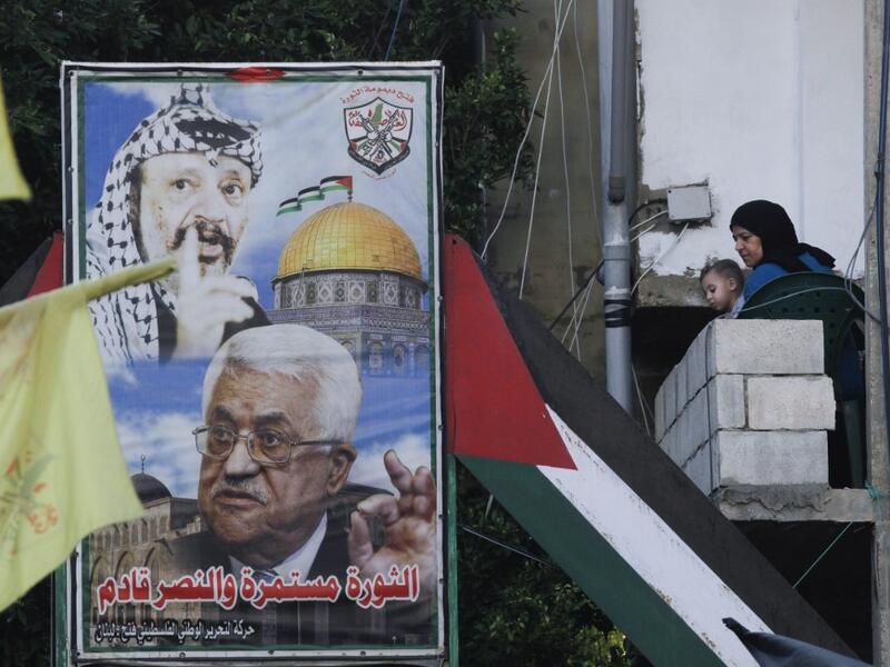 A woman carrying a child looks out her balcony during a demonstration in the Bass Palestinian refugee camp in the Lebanese southern coastal city of Tyre against the Emirati-Israeli agreement, on August 15, 2020. Mahmoud ZAYYAT / AFP