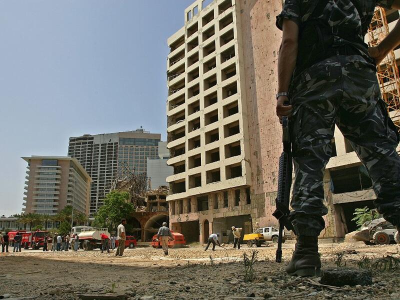 This file photo taken on May 31, 2007 shows a Lebanese policeman securing the site as municipality employees work on closing a crater at the site where a massive car bomb explosion killed former prime minister Rafiq Hariri in Beirut on February 14, 2005. The special tribunal trying the four suspects accused of the 2005 assassination of Lebanon's former prime minister Rafic Hariri is expected to deliver its verdict on on August 18, 2020.  MARWAN NAAMANI / AFP