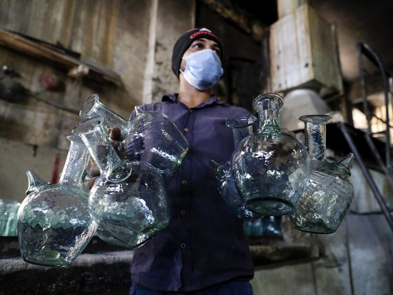 A worker washes jugs at a factory, which is recycling the broken glass as a result of the Beirut explosion, in the northern Lebanese port city of Tripoli on August 25, 2020. The August 4 port explosion ripped through countless glass doors and windows when it laid waste to whole Beirut neighbourhoods, killing at least 190 people and wounding thousands more. Volunteers, non-governmental groups and entrepreneurs salvaged a fraction of the tonnes of broken glass that littered the streets, some of it through rec