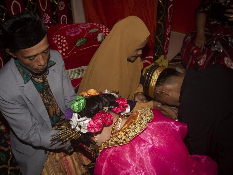 This picture taken on July 25, 2020 shows 18-year-old Lia (C) and her 21-year-old husband Randi (R, not their real names) asking for their parents' blessing after getting married in the village of Tampapadang in Mamuju, West Sulawesi. Child marriage has long been common in traditional communities from the Indonesian archipelago to India, Pakistan and Vietnam, but numbers had been decreasing as charities made inroads by encouraging access to education and women's health services. YUSUF WAHIL / AFP