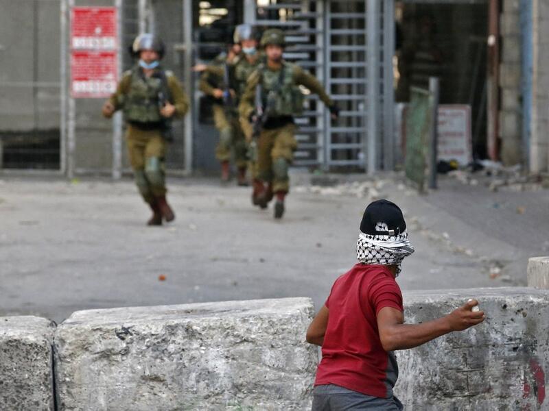 A Palestinian protester hurls stones at Israeli security forces amid clashes in the center of the West Bank city of Hebron, on September 18, 2020. HAZEM BADER / AFP