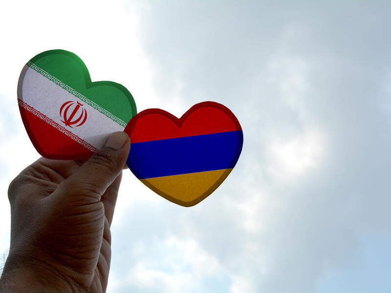 Hand holds a heart Shape Iran and Armenia flag, love between two countries  (Shutterstock)