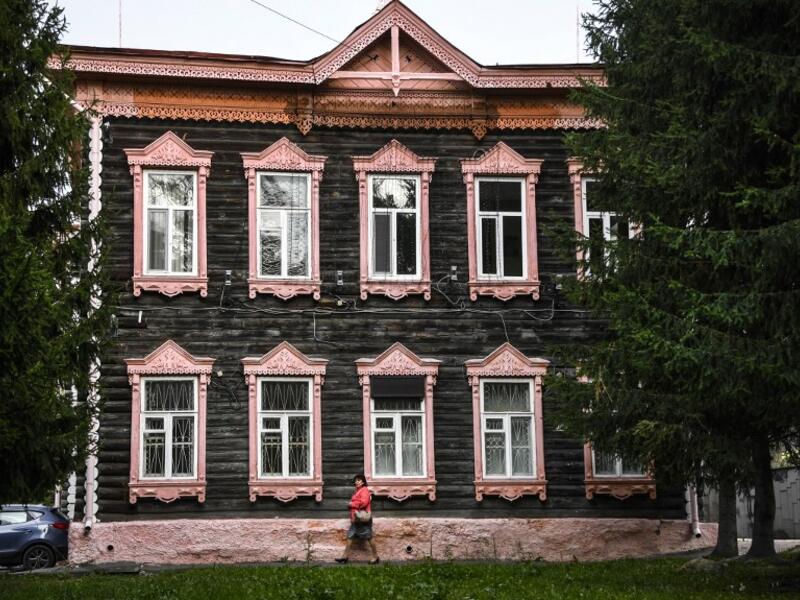 A woman walks past a traditional wooden house in the Siberian city of Tomsk on September 8, 2020. Tomsk is considered to be one of the oldest towns in Siberia founded in 1604. Wooden architecture is one of the symbols of the city of Tomsk, its distinctive feature. Today Tomsk is the only city in Siberia where the background wooden buildings have been preserved, reflecting the manor structure of the city streets. Unfortunately, many wooden houses are not in very good condition and require restoration. Alexan