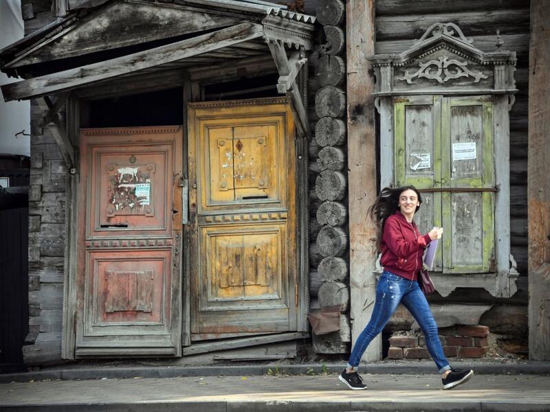 A woman walks past a traditional wooden house in the Siberian city of Tomsk on September 8, 2020. Tomsk is considered to be one of the oldest towns in Siberia founded in 1604. Wooden architecture is one of the symbols of the city of Tomsk, its distinctive feature. Today Tomsk is the only city in Siberia where the background wooden buildings have been preserved, reflecting the manor structure of the city streets. Unfortunately, many wooden houses are not in very good condition and require restoration. Alexan