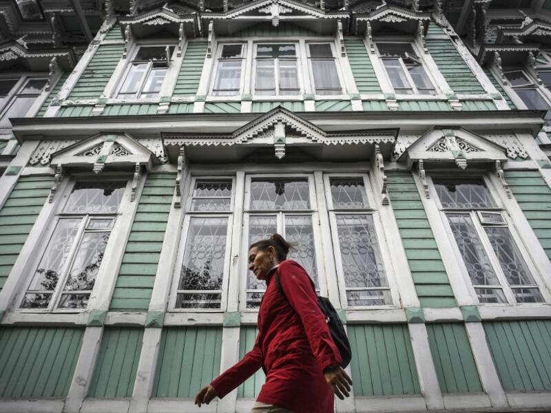 A woman walks past former house of Russian architect Stanislav Khomich, 1904, a traditional wooden house in the Siberian city of Tomsk, on September 8, 2020. Tomsk is considered to be one of the oldest towns in Siberia founded in 1604. Wooden architecture is one of the symbols of the city of Tomsk, its distinctive feature. Today Tomsk is the only city in Siberia where the background wooden buildings have been preserved, reflecting the manor structure of the city streets. Unfortunately, many wooden houses ar