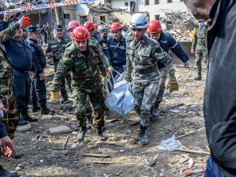Rescuers carry away the body of a victim at the blast site hit by a rocket during the fighting between Armenia and Azerbaijan over the breakaway region of Nagorno-Karabakh, in the city of Ganja, Azerbaijan, on October 11, 2020. Bulent Kilic / AFP