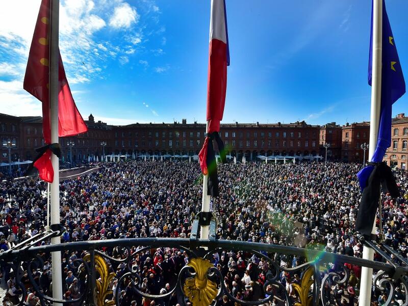 Flags of the City hall are at half-mast as people gather on Place du Capitole in Toulouse on October 18, 2020, in homage to history teacher Samuel Paty two days after he was beheaded by an attacker who was shot dead by policemen. GEORGES GOBET / AFP