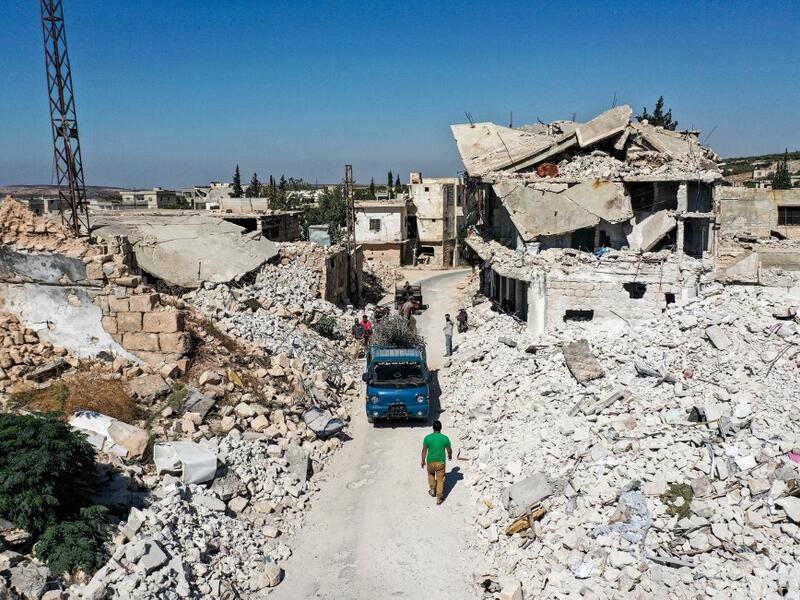People collect scrap steel rods from the rubble and destruction in the aftermath of aerial bombardment in the town of Ihsim in Syria's rebel-held northwestern Idlib province, on October 18, 2020. Omar HAJ KADOUR / AFP