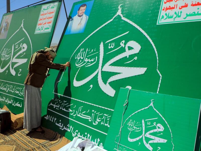 A Yemeni man adjusts the lights on a sign bearing the name of Islam's Prophet Mohammad and the portrait of Shiite Huthi rebel leader Abdul-Malik al-Huthi in the capital Sanaa on October 24, 2020, in response to comments by French President Emmanuel Macron defending cartoons of the Prophet Mohammed. Mohammed HUWAIS / AFP
