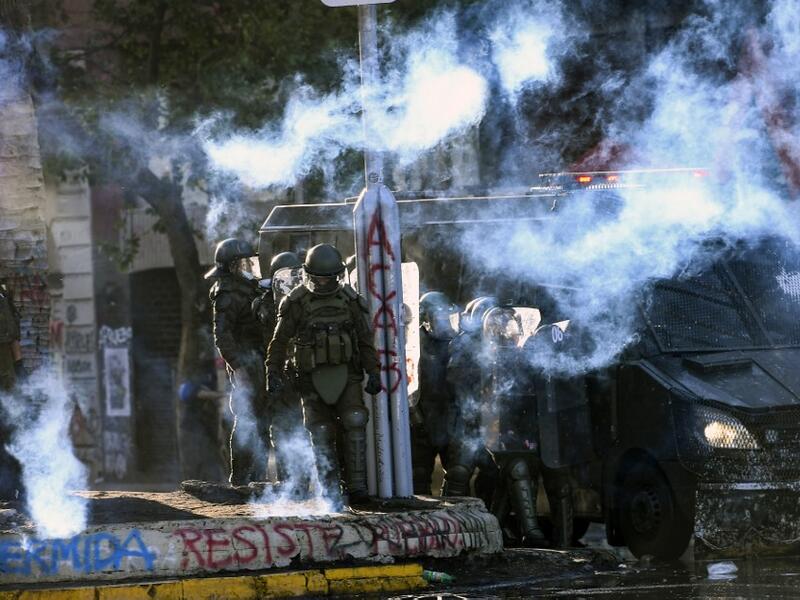 Demonstrators clash with riot police during a protest against Chilean President Sebastian Pinera's government on the constitutional referendum voting day at Plaza Italia square in Santiago on October 25, 2020. A year to the day after more than one million people thronged downtown Santiago in the biggest Chile's social uprising, Chileans vote Sunday on whether to change the country's dictatorship-era constitution seen as underpinning the nation's glaring inequalities. MARTIN BERNETTI / AFP