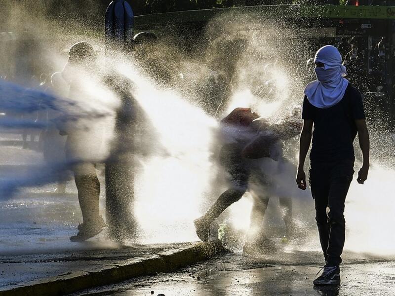 Demonstrators clash with riot police during a protest against Chilean President Sebastian Pinera's government on the constitutional referendum voting day at Plaza Italia square in Santiago on October 25, 2020. A year to the day after more than one million people thronged downtown Santiago in the biggest Chile's social uprising, Chileans vote Sunday on whether to change the country's dictatorship-era constitution seen as underpinning the nation's glaring inequalities. MARTIN BERNETTI / AFP