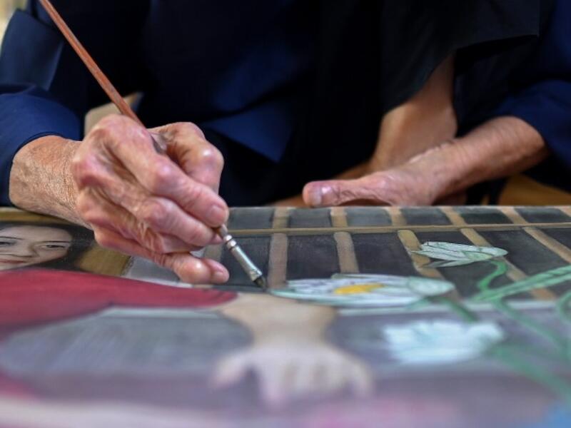 This photograph taken on October 8, 2020 shows 89-year-old Vietnamese artist Mong Bich painting at her house in Bac Ninh province, east of Hanoi. Bich specialises in silk paintings of daily life and ordinary people, women in particular, and ploughed a lonely furrow during many years of war when artists were steered towards the army or frontline workers as subjects. Manan VATSYAYANA / AFP