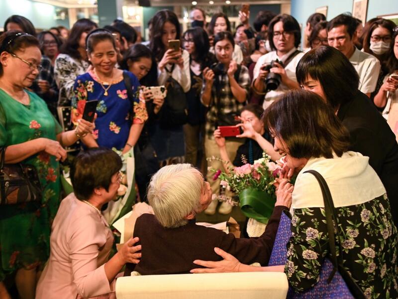 This photograph taken on October 22, 2020 shows guests greeting 89-year-old Vietnamese artist Mong Bich during the opening of her first solo exhibition at the French Cultural Centre in Hanoi. Bich specialises in silk paintings of daily life and ordinary people, women in particular, and ploughed a lonely furrow during many years of war when artists were steered towards the army or frontline workers as subjects. Manan VATSYAYANA / AFP