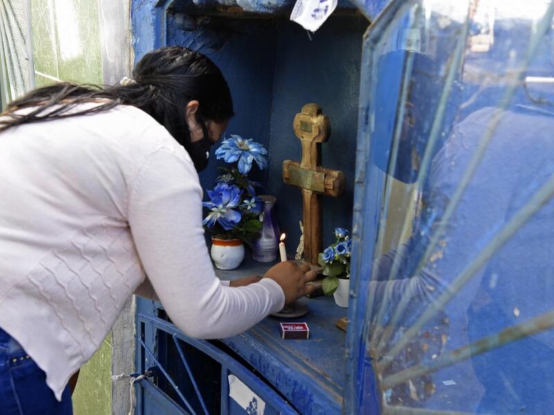 A woman lights a candle as she visits a relative's tomb at a cemetery in Asuncion on November 1, 2020, on All Saints' Day. Municipal cemeteries in Paraguay will be open to the public only on November 1 and 2, during All Saints' Day and the Day of the Dead, amid the new coronavirus pandemic. NORBERTO DUARTE / AFP