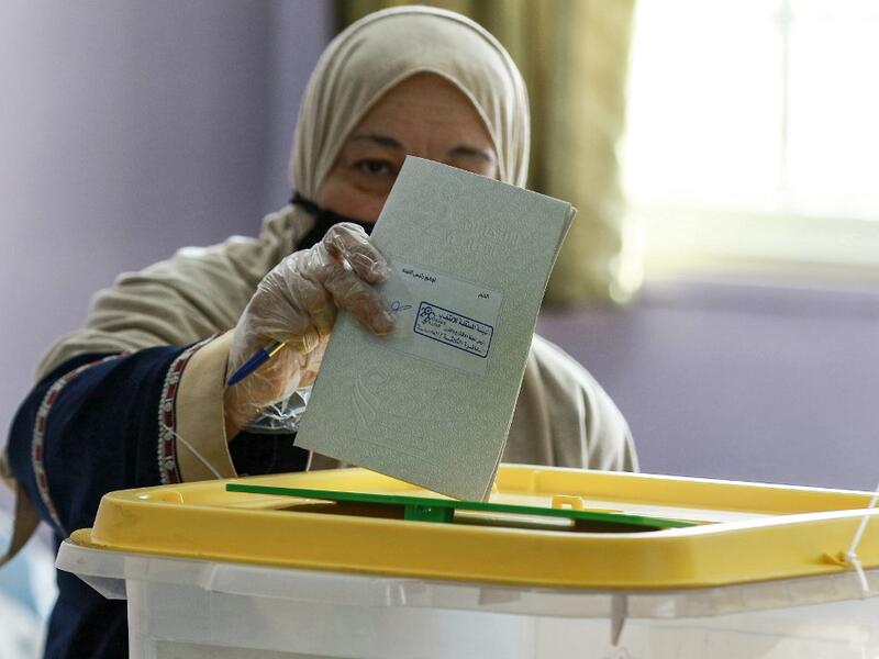A voter, mask-clad due to the COVID-19 coronavirus pandemic, casts her ballot at a polling station in Jordan's capital Amman on November 10, 2020, during the 2020 general election. (AFP/File Photo)