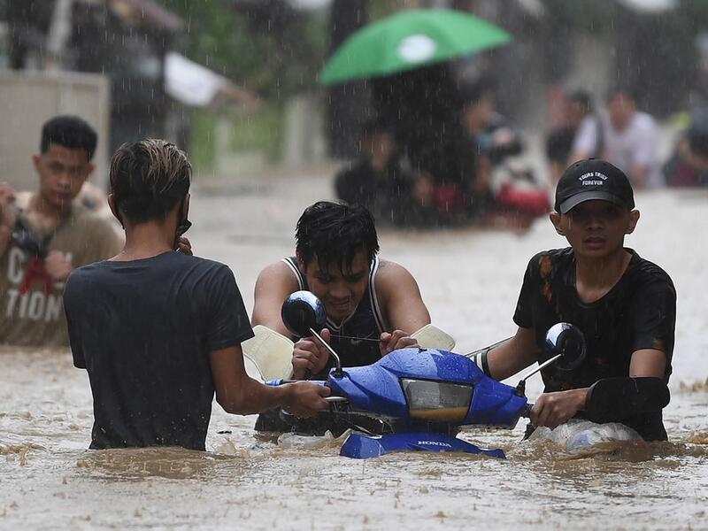 Residents carry their belongings as they make their way through a flooded street to shelter after Typhoon Vamco hit, in Marikina City, suburban Manila on November 12, 2020. Ted ALJIBE / AFP
