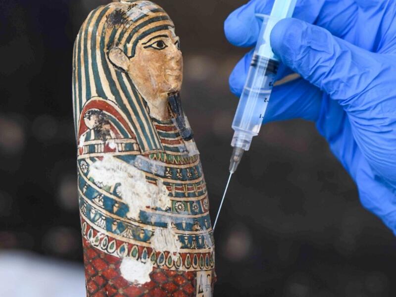 An archaeologist cleans a statue during the unveiling of an ancient treasure trove of more than a 100 intact sarcophagi, at the Saqqara necropolis 30 kms south of the Egyptian capital Cairo, on November 14, 2020. Egypt announced the discovery of an ancient treasure trove of more than a 100 intact sarcophagi, the largest such find this year. The sealed wooden coffins, unveiled on site amid fanfare, belonged to top officials of the Late Period and the Ptolemaic period of ancient Egypt. They were found in thre