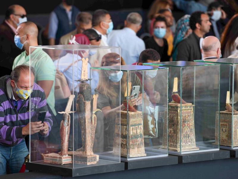 A picture shows statues and funerary masks on display during the unveiling of an ancient treasure trove of more than a 100 intact sarcophagi, at the Saqqara necropolis 30 kms south of the Egyptian capital Cairo, on November 14, 2020. Egypt announced the discovery of an ancient treasure trove of more than a 100 intact sarcophagi, the largest such find this year. The sealed wooden coffins, unveiled on site amid fanfare, belonged to top officials of the Late Period and the Ptolemaic period of ancient Egypt. Th