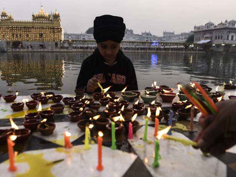 A Sikh boy lights oil lamps on the occasion of Bandi Chhor Divas, a Sikh festival coinciding with Diwali, the Hindu festival of Light, at the Golden Temple in Amritsar on November 14, 2020. NARINDER NANU / AFP