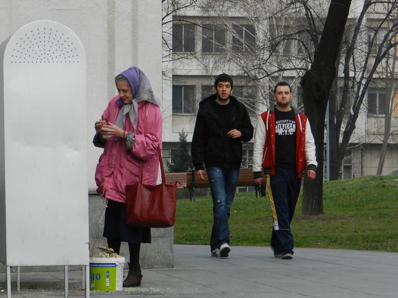 An elderly woman lights candles outside  the Temple of Saint Sava in Belgrade, Serbia /Photo by Ewelina Lepionko