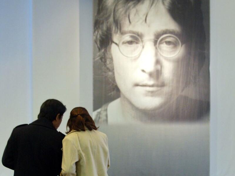 In this file photo taken on December 09, 2002 a Japanese couple place bouquets in front of a big portrait of former Beatle John Lennon at the John Lennon Museum before a charity concert to commemorate the 22nd anniversary of his death in Saitama, suburban Tokyo, 09 December 2002. John Lennon's career was cut short 40 years ago, on December 8, 1980, when he was shot dead in New York. AFP