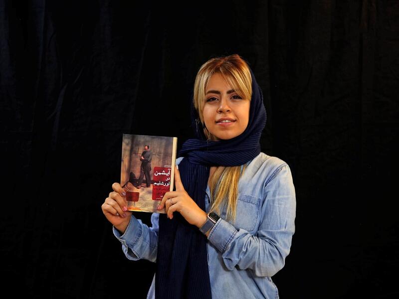Employee Peghah Jafarieh poses with a bestselling book of the Saless Publishing House in Iran's capital Tehran, on October 11, 2020. ATTA KENARE / AFP