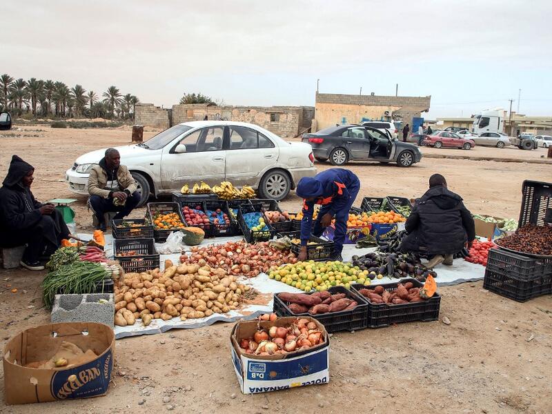 Produce vendors sit by their fruit and vegetable merchandise in the open in the city of Tawergha, some 200 kilometres (125 miles) east of Libya's capital close to the port city of Misrata, on December 12, 2020. When Libyan dictator Moamer Kadhafi was toppled, people took revenge on those they saw as his supporters -- including the entire town of Tawergha, whose 40,000 residents were forced to flee. Now, almost a decade later since militia forces rampaged through the town torching homes, destroying buildings