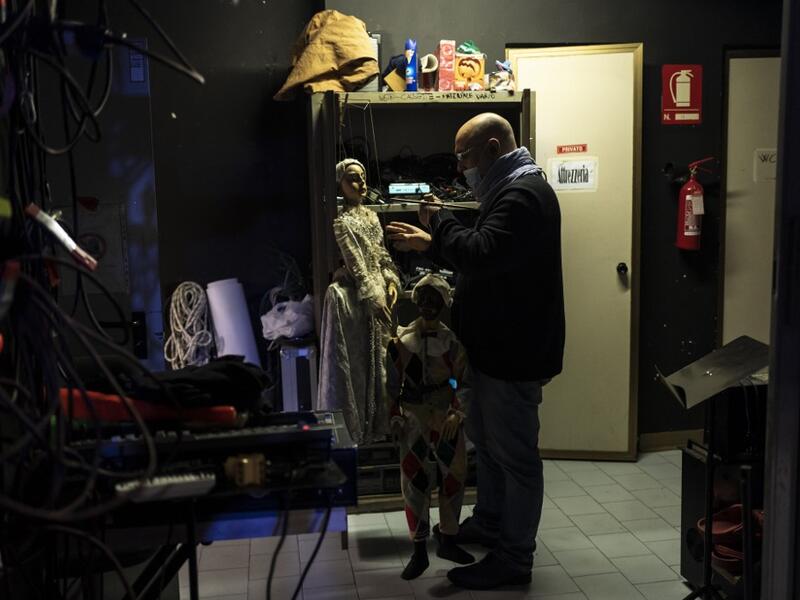 Marco Grilli holds two puppets backstage at the " Alfa Theatre" in Turin, on November 30, 2020. The Grilli family has a collection of more than 20,000 objects from around the world, everything from theatres, marionettes and glove puppets to shadow figures and silhouettes. A long-time dream of Grilli and his wife Mariarosa, 78, the museum is due to open in 2023 in Turin, financed both privately and publicly with the help of different institutions.  Marco Bertorello / AFP