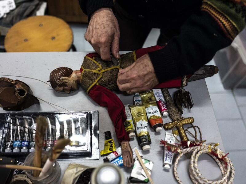 Augusto Grilli repairs a puppet in his " Alfa Theatre" laboratory in Turin, on November 30, 2020. The Grilli family has a collection of more than 20,000 objects from around the world, everything from theatres, marionettes and glove puppets to shadow figures and silhouettes. A long-time dream of Grilli and his wife Mariarosa, 78, the museum is due to open in 2023 in Turin, financed both privately and publicly with the help of different institutions.  Marco Bertorello / AFP