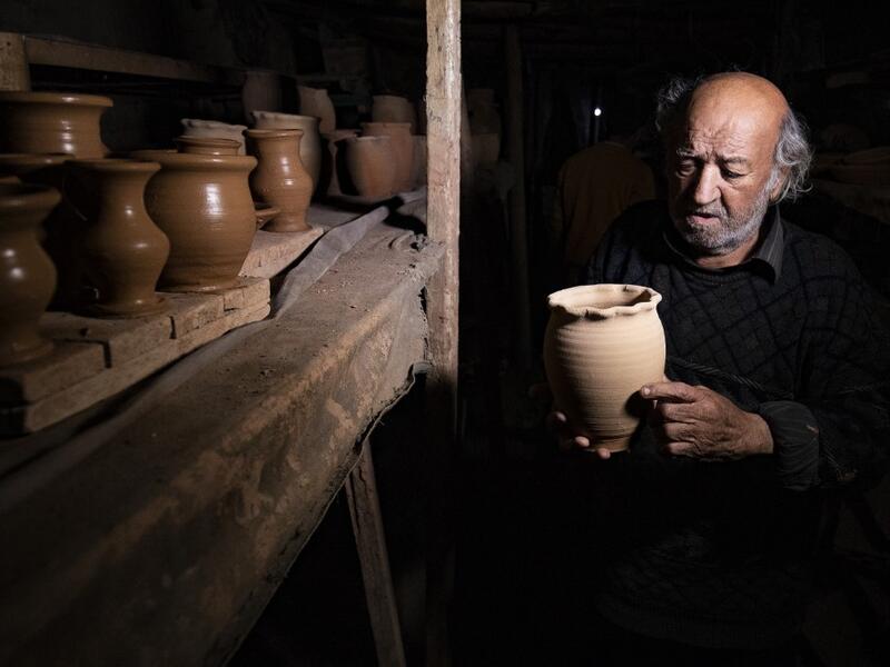 Syrian-Armenian potter Misak Antranik Petros arranges pottery vases at his workshop located inside an ancient mud-brick house near the city of Qamishli in Syria's northeastern Hasakeh province, on December 19, 2020. Petros was only a teenager when he had to take over for his sick father and become the main potter of the family. He has since become a master of the craft, and is keen to pass his skills on.  Delil SOULEIMAN / AFP