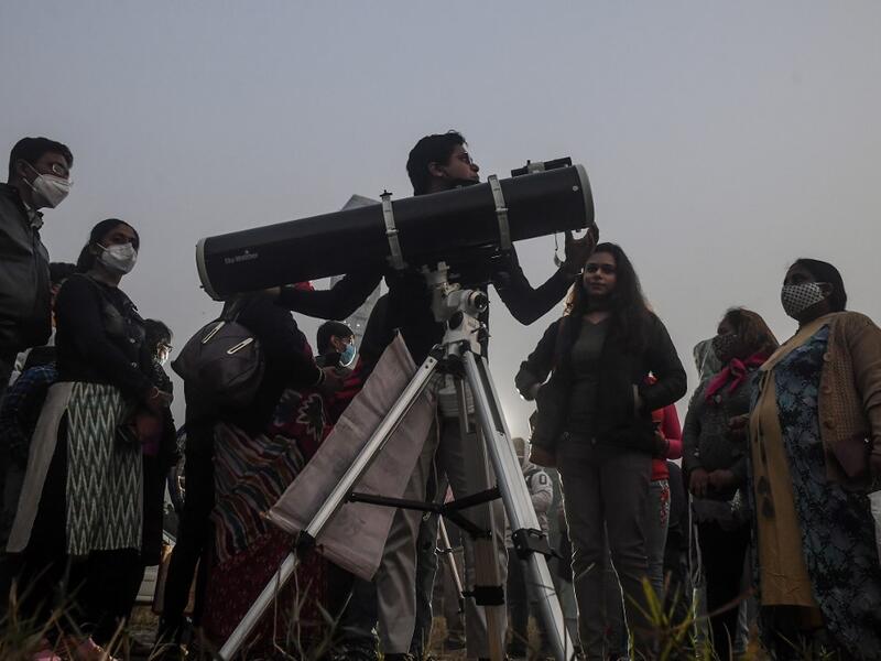 People stand in a queue to see a 'great conjunction' of Jupiter and Saturn at the Maidan area in Kolkata on December 21, 2020. Dibyangshu SARKAR / AFP