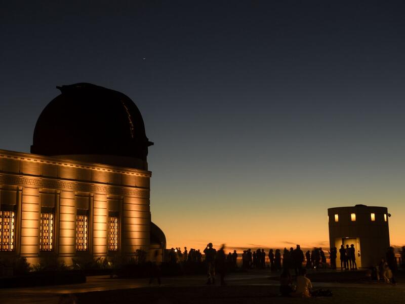 People watch the planets Jupiter and Saturn, upper left, above a telescope dome, during the great conjunction as seen from the Griffith Observatory on the same day as the winter solstice, December 21, 2020 in Los Angeles, California. The great conjunction refers to the astronomical alignment of Jupiter and Saturn, the closest for nearly 400 years. Patrick T. Fallon / AFP