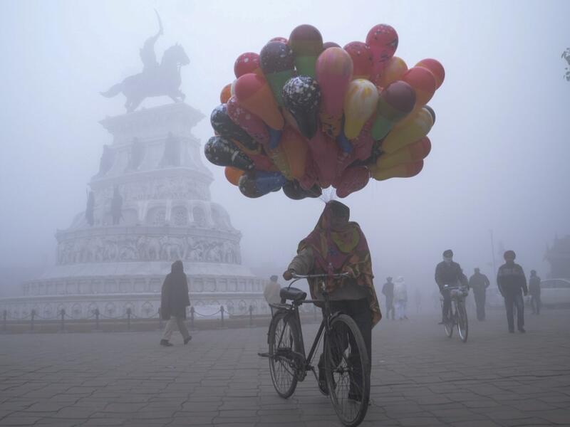 A balloon seller walks along Heritage street amid dense fog on a cold day on New Year's Day, in Amritsar on January 1, 2021. NARINDER NANU / AFP