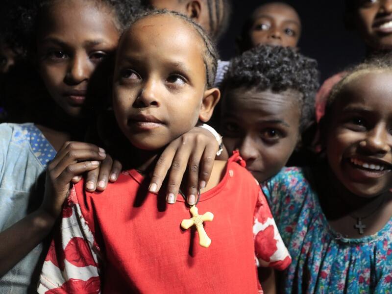 Ethiopian refugee children who fled the Tigray conflict attend the Coptic Christmas midnight mass with local believers, in front of an Ethiopian Orthodox church built by former Ethiopian refugees, at a village next to Um Raquba refugee camp in Gedaref, eastern Sudan, late on January 6, 2021. ASHRAF SHAZLY / AFP