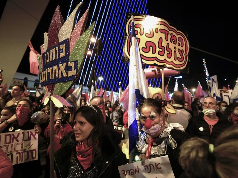 Israelis lift placards and flags as they take part in a demonstration against Prime Minister Benjamin Netanyahu at the entrance to the city in Jerusalem, amid the coronavirus pandemic crisis, on January 9, 2021. MENAHEM KAHANA / AFP