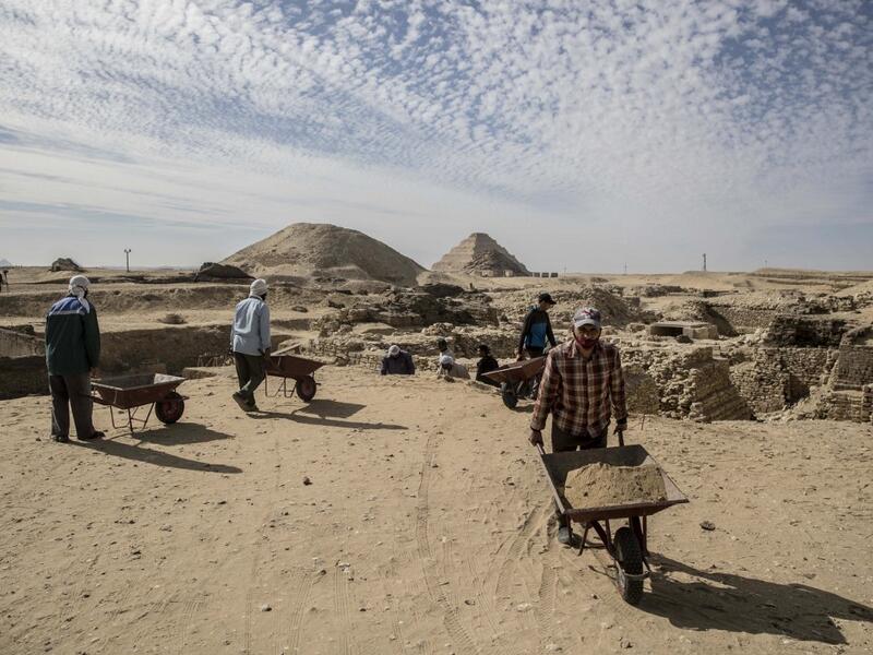 Workers excavate a site during the official announcement of the discovery by an Egyptian archaeological mission of a new trove of treasures at Egypt's Saqqara necropolis south of Cairo, on January 17, 2021. The discovery at the necropolis which lies 30kms south of the Egyptian capital, includes the funerary temple of Queen Naert, wife of King Teti, as well as burial shafts, coffins, and mummies dating back to nearly 3000 years ago during the New Kingdom. Khaled DESOUKI / AFP