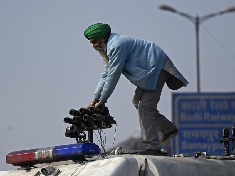A farmer stands on a police vehicle during a tractor rally as farmers continue to demonstrate against the central government's recent agricultural reforms in New Delhi on January 26, 2021. Money SHARMA / AFP