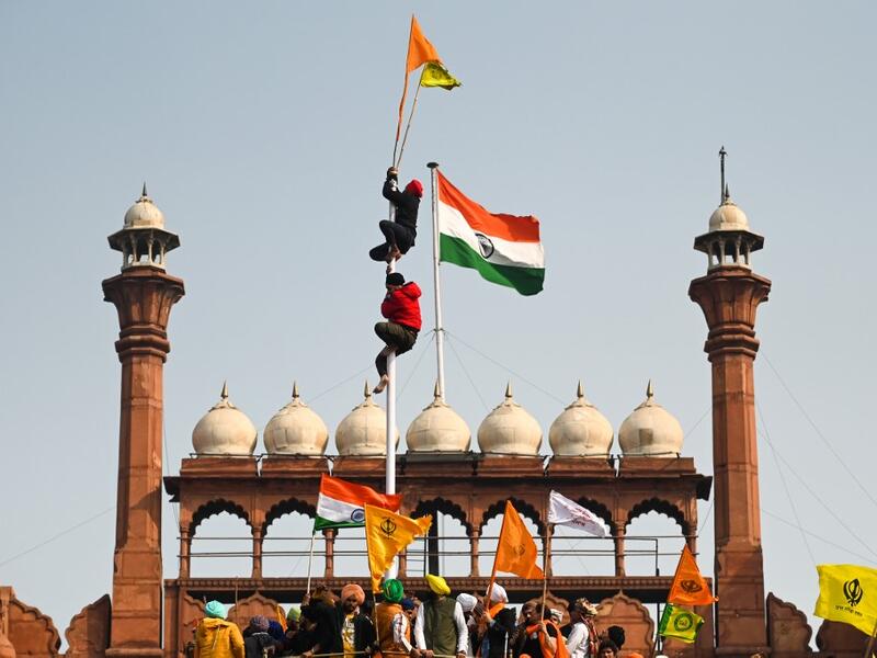 Protesters climb a flagpole at the ramparts of the Red Fort as farmers continue to demonstrate against the central government's recent agricultural reforms in New Delhi on January 26, 2021. Sajjad HUSSAIN / AFP