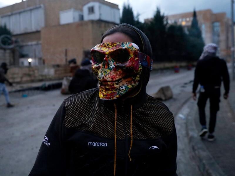 A Lebanese anti-government protester wears a mask during clashes with security forces in front of the Serail (headquarters of the Governorate), in the northern port city of Tripoli, following a demonstration to protest against the economic situation, on January 28, 2021. Tripoli was already one of Lebanon's poorest areas before the coronavirus pandemic piled new misery onto a chronic economic crisis. Many of its residents have been left without an income since Lebanon imposed a full lockdown earlier this mo