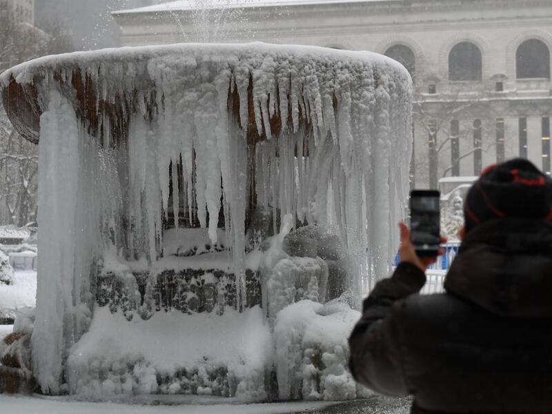 A person takes a picture of The Josephine Shaw Lowell Memorial Fountain covered in ice during a winter storm on February 1, 2021 in New York City. A powerful winter storm is set to dump feet of snow along a stretch of the US east coast including New York City on February 1, 2021, after blanketing the nation's capital. Angela Weiss / AFP