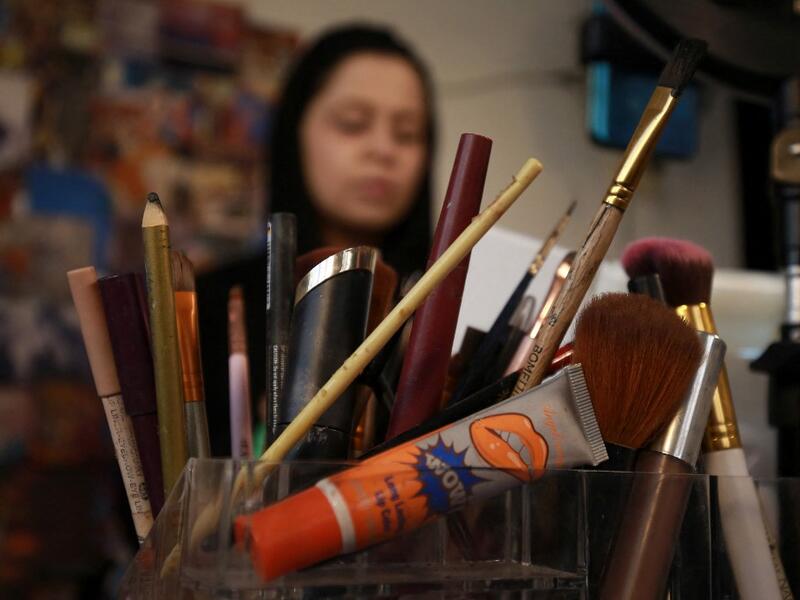 Jordanian make-up artist Alaa Bliha, 27, is pictured in front of her crayons and brushes, in the basement apartment where she lives with her mother and young brother in the capital Amman, on February 2, 2021. Bliha has beaten the lockdown blues and shot to online fame with videos of herself imitating famous figures from across the Arab world and beyond. From Donald Trump and Queen Elizabeth II to Egyptian superstars like singer Umm Kalthum and actor Adel Imam, her characters have made Alaa Bliha a star in h