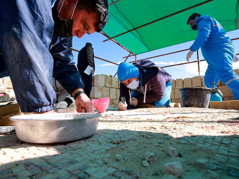 Workers employed by a pilot project run by the UN cultural agency UNESCO, restore a mosaic floor at an ancient church complex, in the small town of Rihab, some 70 kilometres north of the Jordanian capital Amman, on February 9, 2021. In the ruins of the ancient Byzantine church in Jordan, local townspeople and Syrian refugees work side by side on a project that unites preserving cultural heritage and fighting poverty.  Khalil MAZRAAWI / afp