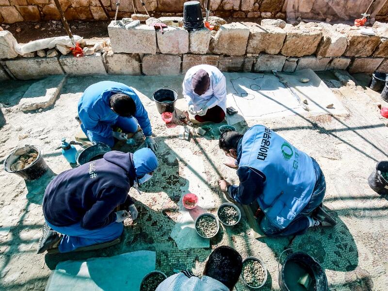 Workers employed by a pilot project run by the UN cultural agency UNESCO, restore a mosaic floor at an ancient church complex, in the small town of Rihab, some 70 kilometres north of the Jordanian capital Amman, on February 9, 2021. In the ruins of the ancient Byzantine church in Jordan, local townspeople and Syrian refugees work side by side on a project that unites preserving cultural heritage and fighting poverty.  Khalil MAZRAAWI / afp