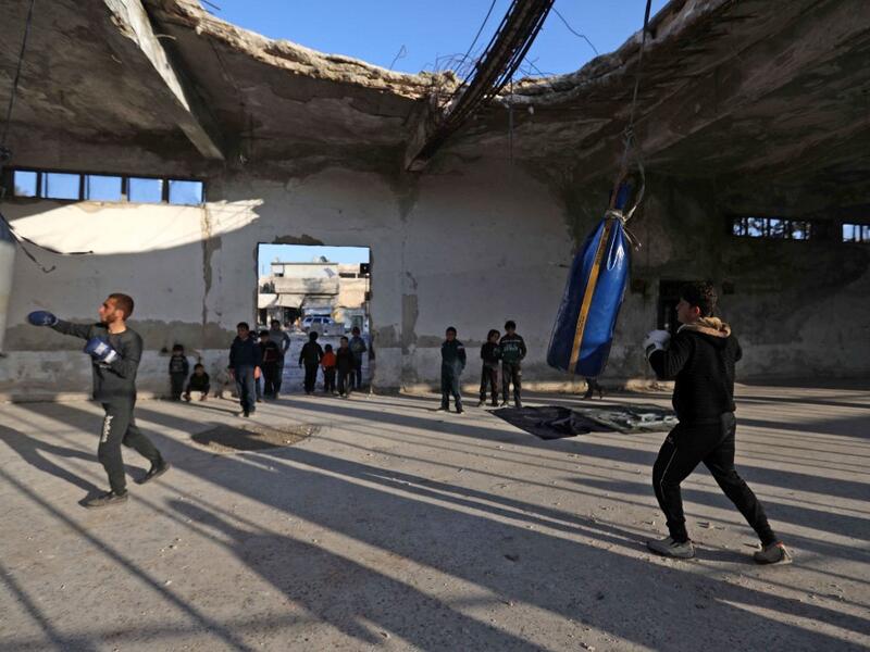 Syrian youths take part in a boxing workout held by local boxer Ahmad Dwara (unseen) inside a damaged building in the town of Atareb in the rebel-held western countryside of Syria's Aleppo province, on February 11, 2021. AAREF WATAD / AFP