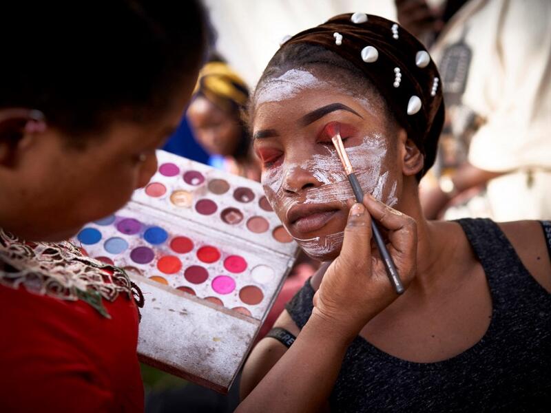 A make up artist gets a model ready, in the backstage, prior to take part, in a fashion show as part of the first edition of the International Gold Fair Afrik'Or, in Bamako, on February 12, 2021. The Princess of Burundi Esther Kamatari, selected 34 women among gold mines workers in southern Mali, to walk down the catwalk for a fashion show organised during the International Gold Fair. Gold represents 15% of Mali's exports and more than 20% of its GDP estimated at nearly US$20 billion by the end of 2019. MIC