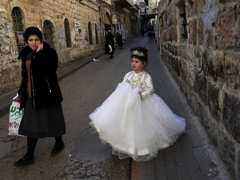 An Ultra-Orthodox Jewish child dressed in a bride's to celebrate Purim walks in the street a day ahead of the official holiday, in the Mea Shearim neighbourhood in Jerusalem, on February 24, 2021. The carnival-like Purim holiday is celebrated with parades and costume parties to commemorate biblical story of the deliverance of the Jewish people from a plot to exterminate them in the ancient Persian empire , as recorded in the Book of Esther. MENAHEM KAHANA / AFP