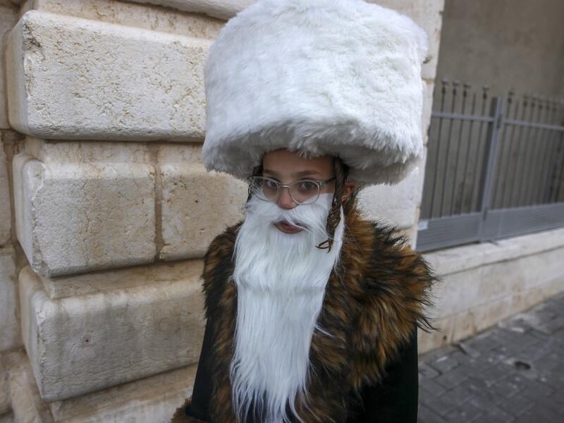 An Ultra-Orthodox Jewish child, wearing a fake beard and a shtreimel to celebrate Purim, walks in Jerusalem's the Mea Shearim neighborhood in, on February 25, 2021. Israel imposed a night-time curfew for three nights to curb the spread of the coronavirus during the Jewish holiday of Purim. The carnival-like Purim holiday is celebrated with parades and costume parties to commemorate biblical story of the deliverance of the Jewish people from a plot to exterminate them in the ancient Persian empire, as record
