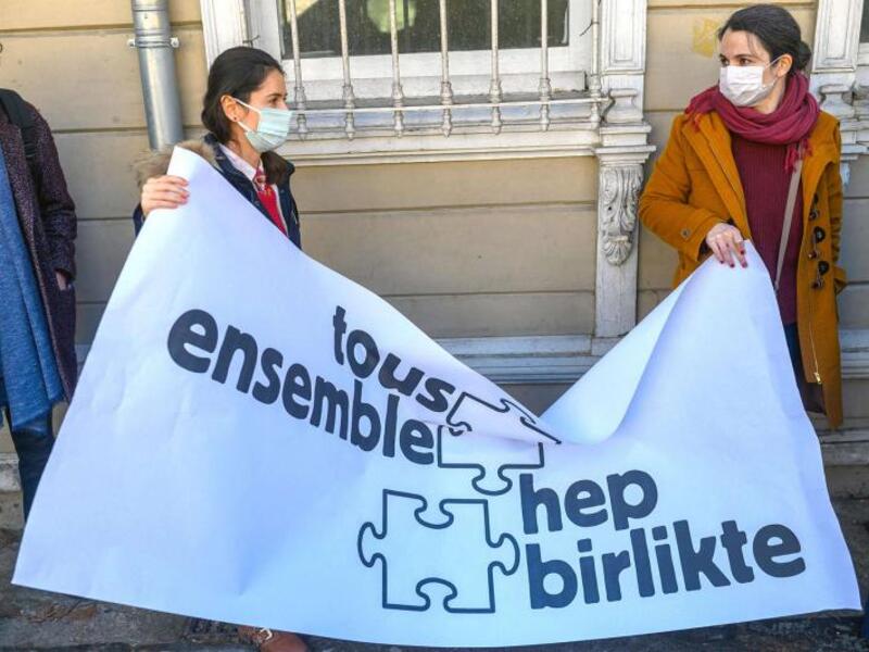 Two women hold a banner reading “All together” as Galatasaray University’s French teachers without working permits give a press conference in front of Galatasaray university in Istanbul on February 23, 2021. (AFP)