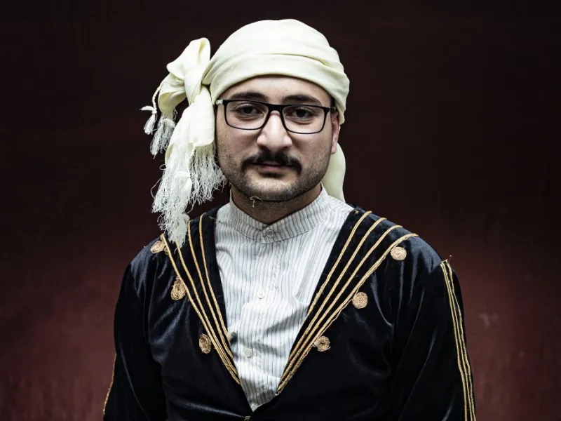 A Syrian Kurdish man in traditional attire poses for a picture 