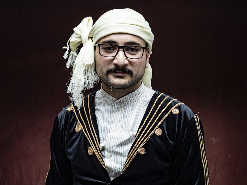 A Syrian Kurdish man in traditional attire poses for a picture 